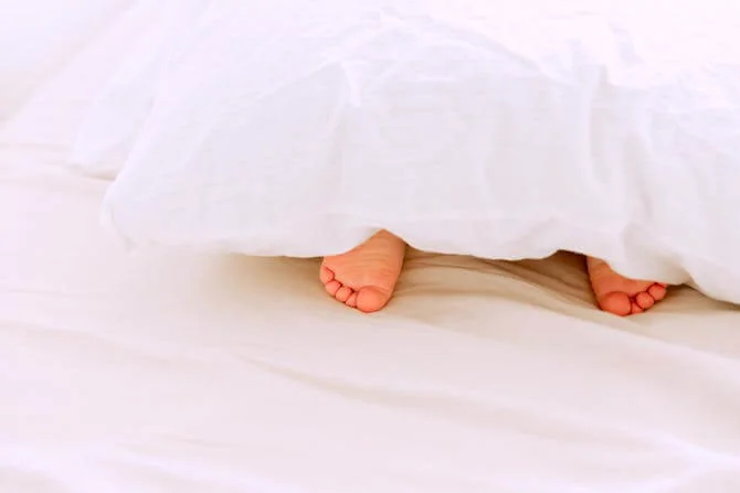 some feet poking out from under a duvet