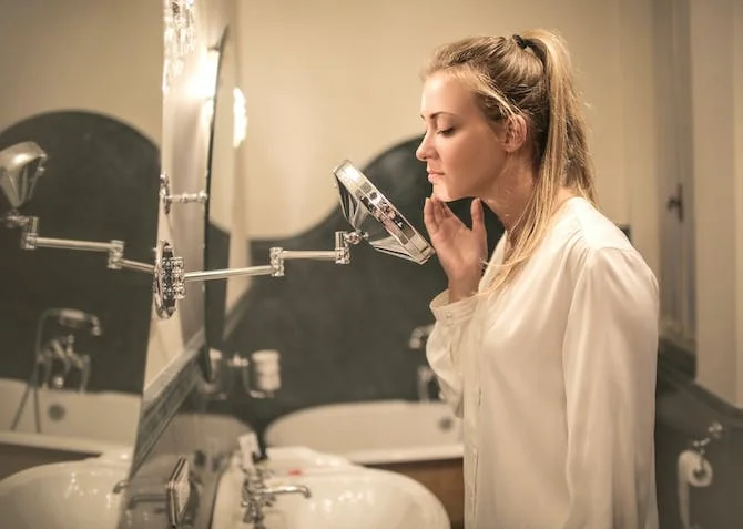 woman checking her skin in the mirror