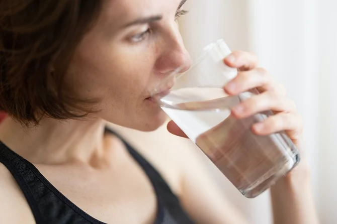 Woman in black tank top drinking water