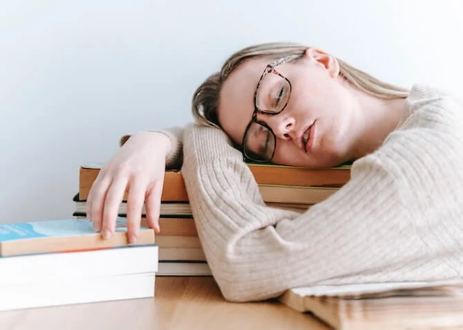 woman taking a nap using books as a pillow