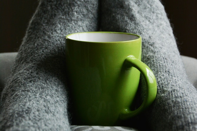 woman drinking hot drink in bed and warm clothes