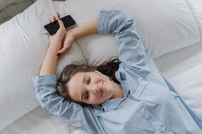 woman listening to sleep playlist in bed